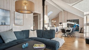 Ein modernes Wohnzimmer mit einem Ecksofa, einem Couchtisch und einem Essbereich mit Tisch und Stühlen.
