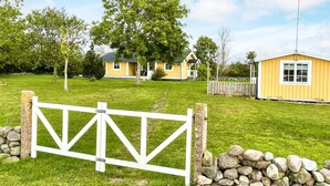 A gated property with a stone wall, a grassy lawn, and a yellow building. - 4 Person Holiday Home in Lottorp (Löttorp)