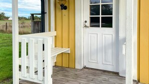 A white porch with a bench, a yellow wall, and a white door with a window. - 4 Person Holiday Home in Lottorp (Löttorp)
