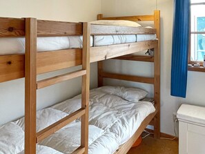 A bunk bed with a wooden frame and white bedding.