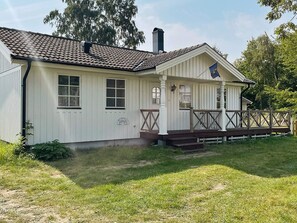 A white building with a tiled roof, a porch with a railing, and a flag. - 8 Person Holiday Home in Borgholm (Borgholm)