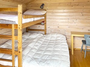 A bunk bed with a wooden frame, a single bed below, and a small table with a chair. - 8 Person Holiday Home in Borgholm (Borgholm)