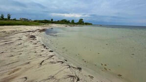 A beach with clear water, a sandy shore, and a building in the background. - 8 Person Holiday Home in Borgholm (Borgholm)