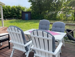 An outdoor deck with a table and chairs, a small shed, and a grassy yard.