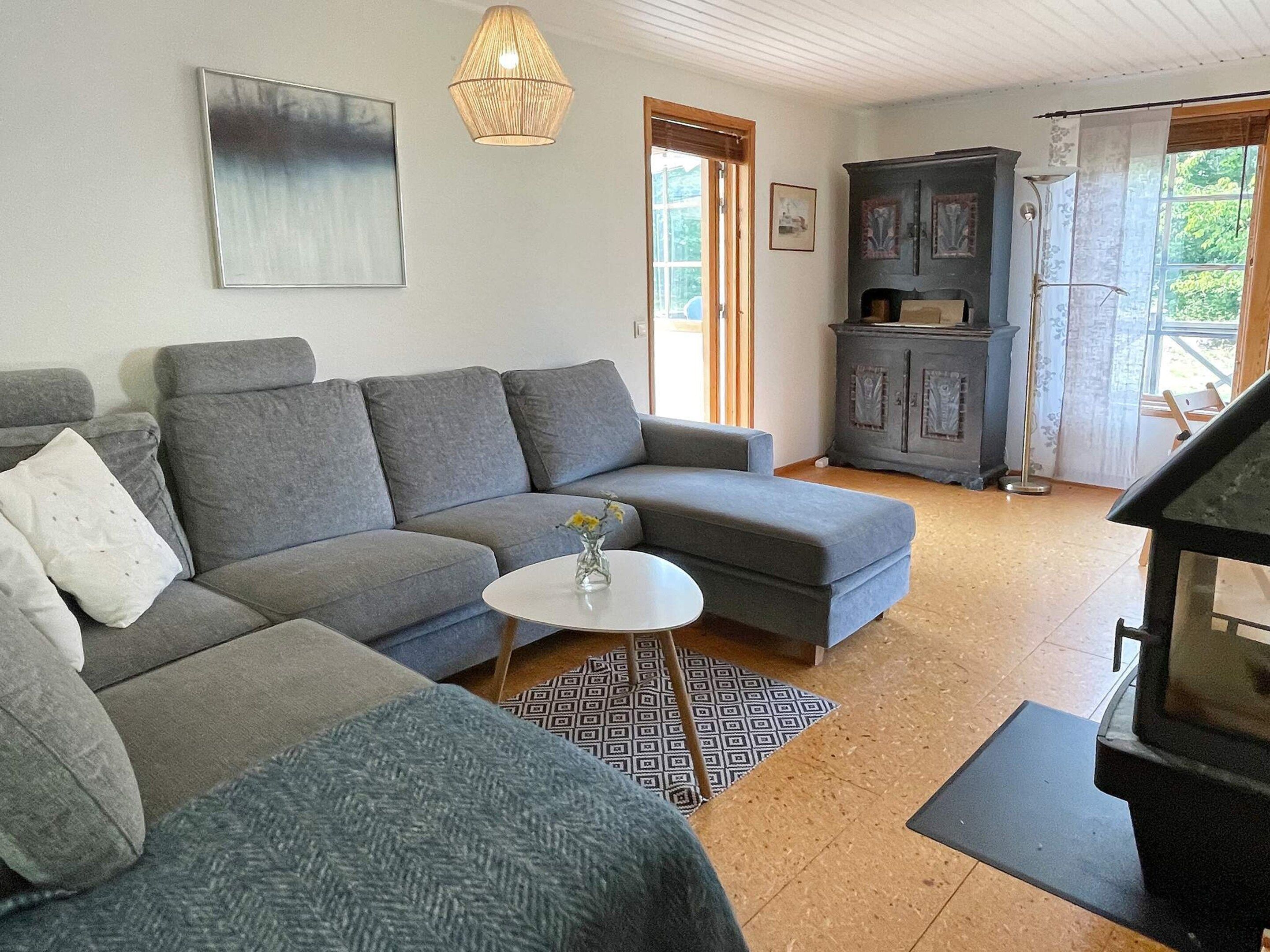 Ett vardagsrum med en grå soffa, ett litet vitt bord och ett skåp.