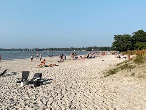 A sandy beach with lounge chairs and people sunbathing. - 8 Person Holiday Home in Borgholm (Borgholm)