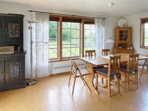 A dining area with a wooden table and chairs, a cabinet with glass doors, and a window with a view of greenery. - 8 Person Holiday Home in Borgholm (Borgholm)
