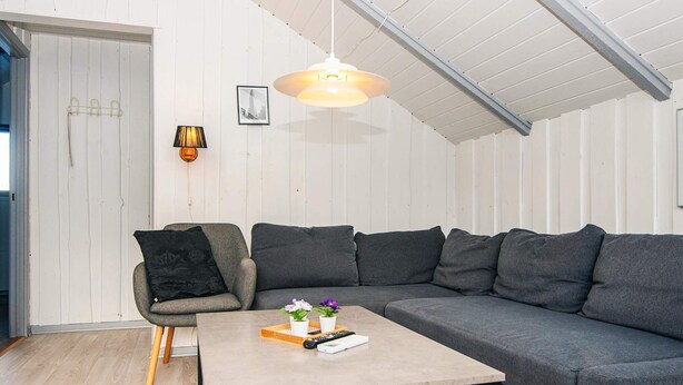 A modern living room with a grey sectional sofa, a small wooden coffee table, a single armchair, and a pendant light. - 6 Person Holiday Home in Give (Give)