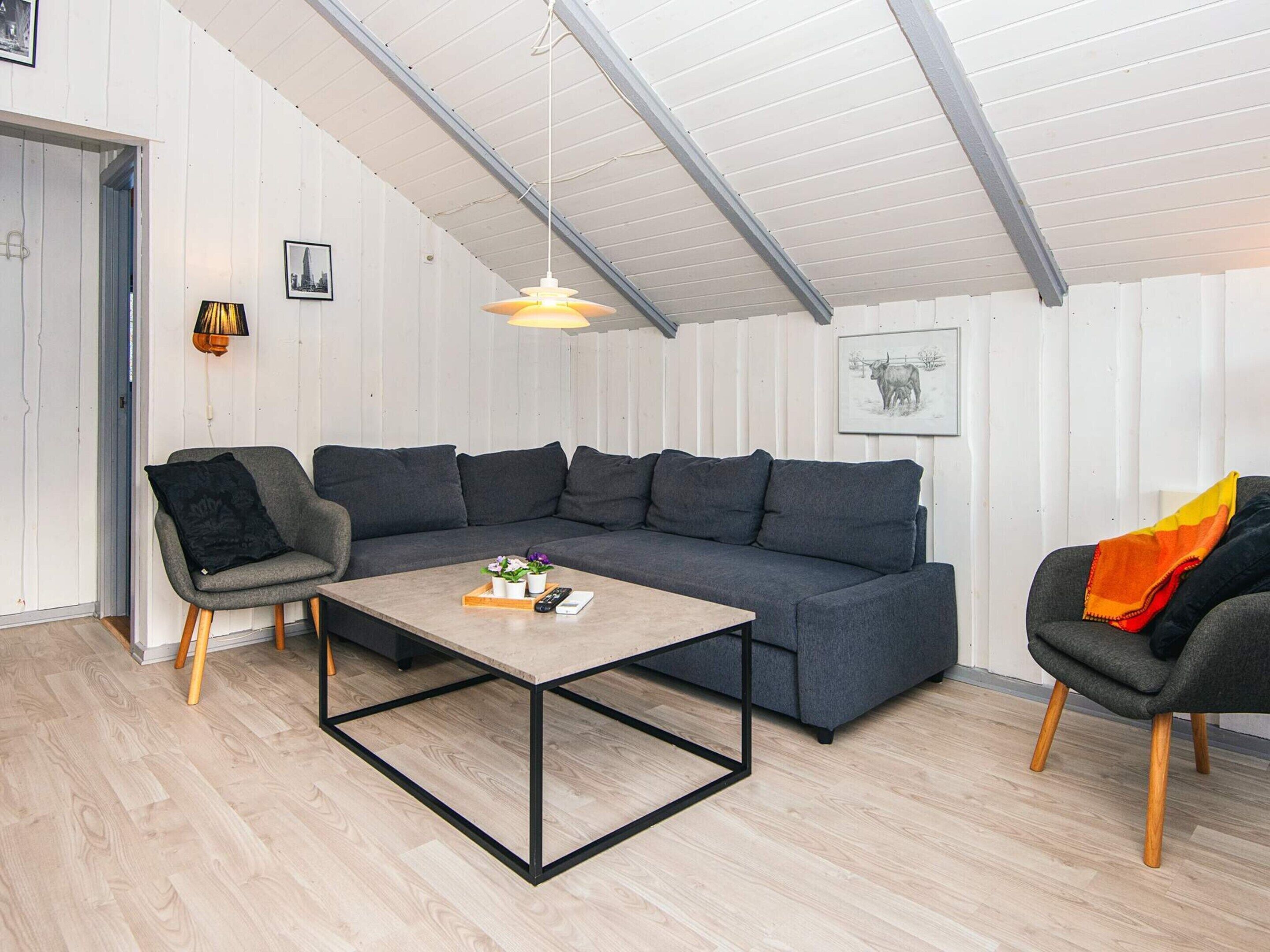 A modern living room with a sectional sofa, a coffee table, and two armchairs.