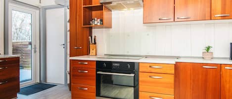 A modern kitchen with wooden cabinets, a built-in oven, and a stainless steel range hood.