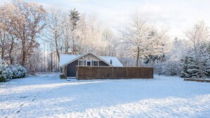 A cabin with a wooden deck and a metal roof, surrounded by snow-covered trees. - 6 Person Holiday Home in Give (Give)