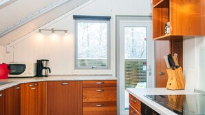 A modern kitchen with wooden cabinets, a microwave, a coffee maker, and a knife block. - 6 Person Holiday Home in Give (Give)