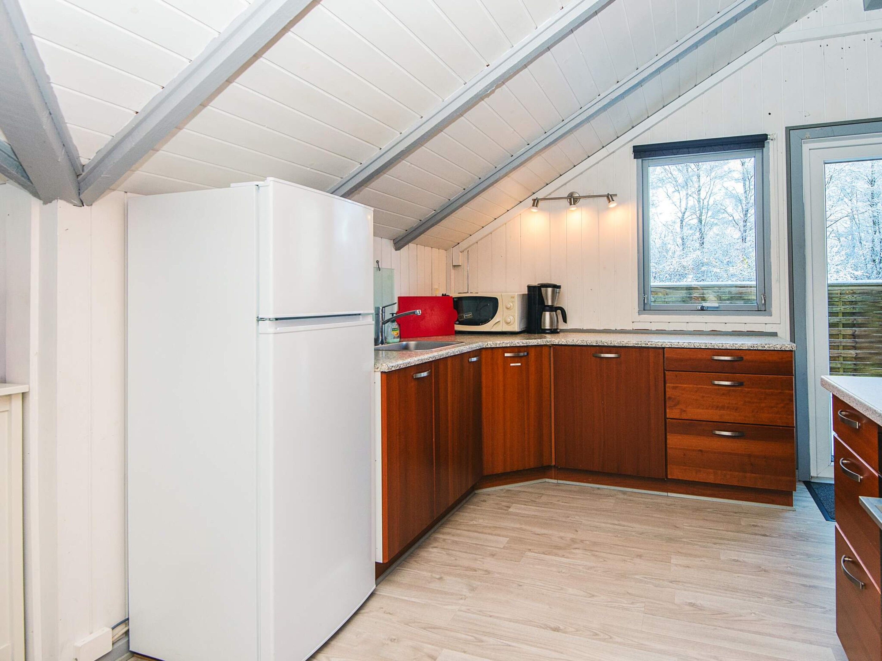 A compact kitchen with wooden cabinets, a white refrigerator, a microwave, and a coffee maker.