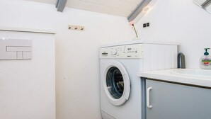 A compact laundry room with a front-loading washing machine, a sink, and a toilet. - 6 Person Holiday Home in Give (Give)
