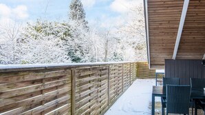 A wooden deck with a metal railing, a table with chairs, and a view of snow-covered trees. - 6 Person Holiday Home in Give (Give)