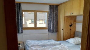 Une chambre avec deux lits, une fenêtre avec des rideaux, une lampe de chevet et une petite table.