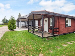 A red wooden cabin with a porch, a door, and a window. - 6 Person Holiday Home in Haderslev (Haderslev)