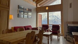 A cozy room with a wooden table and chairs, a red sofa, and a fireplace. - Stunning Apartment With Valley and Mountains (Veysonnaz)