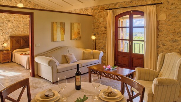 A dining area with a table set for two, a bottle of wine, and a fruit centerpiece. - Agroturismo Roqueta (Maria de la Salut)