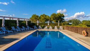 A swimming pool with lounge chairs and umbrellas, surrounded by greenery and trees. - Agroturismo Roqueta (Maria de la Salut)