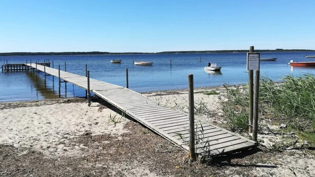 Eine hölzerne Pier, die sich in ruhiges Wasser erstreckt, mit mehreren in der Nähe verankerten Booten.