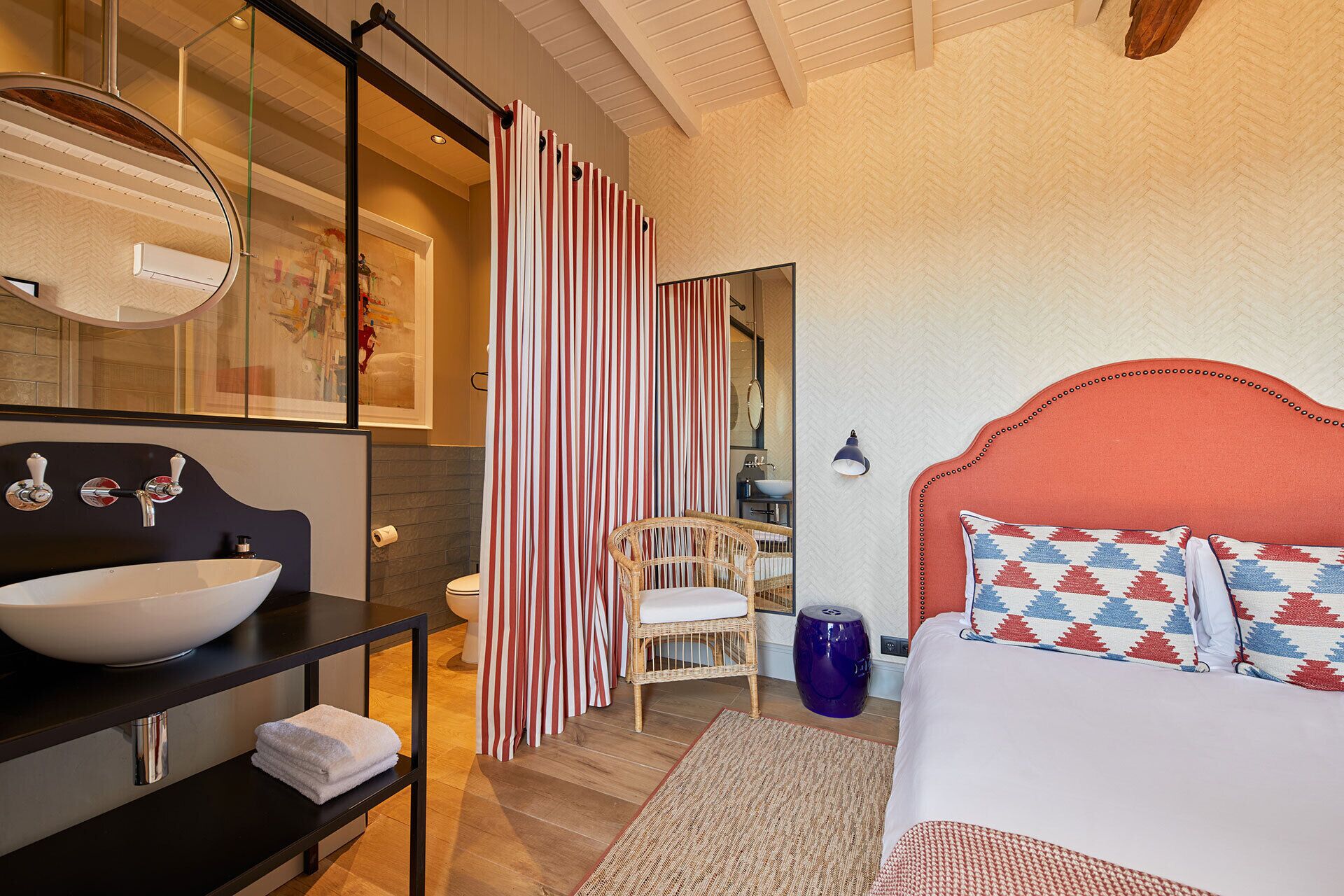 A modern bedroom with a large bed, a white sink, a mirror, and a striped shower curtain.