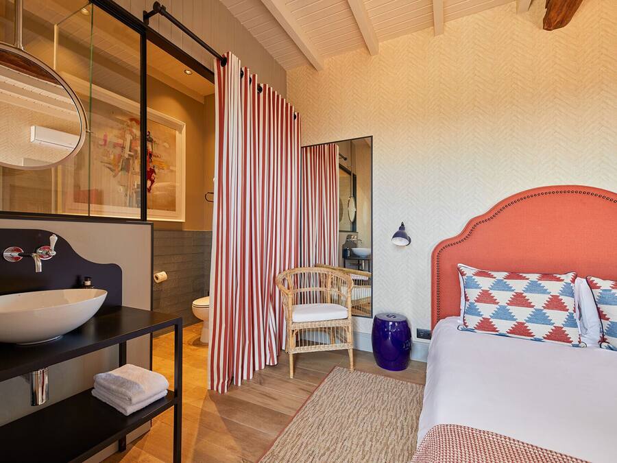 A modern bedroom with a large bed, a white sink, a mirror, and a striped shower curtain.