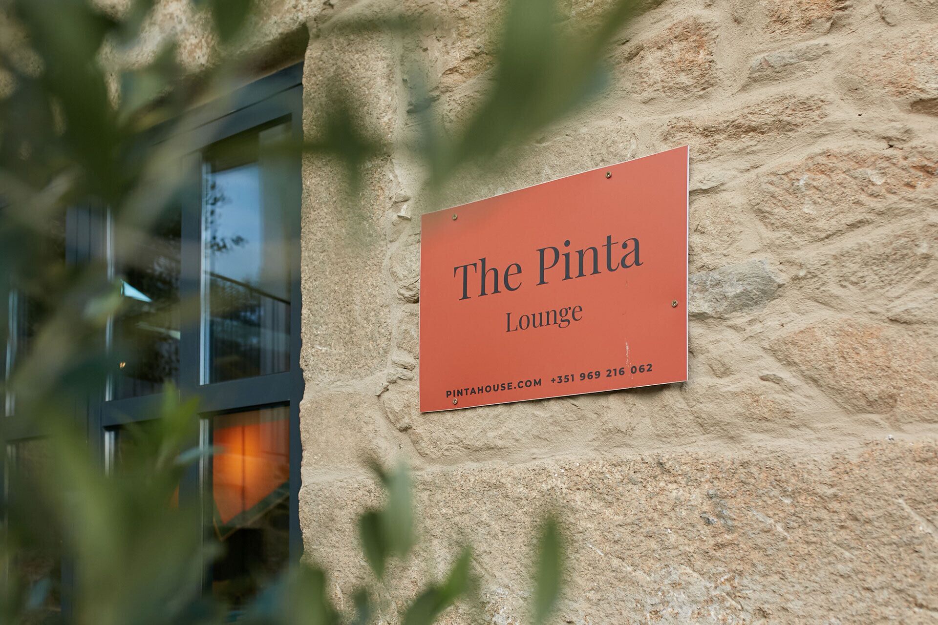Un letrero que dice 'The Pintah Lounge' sujeto a una pared de piedra.