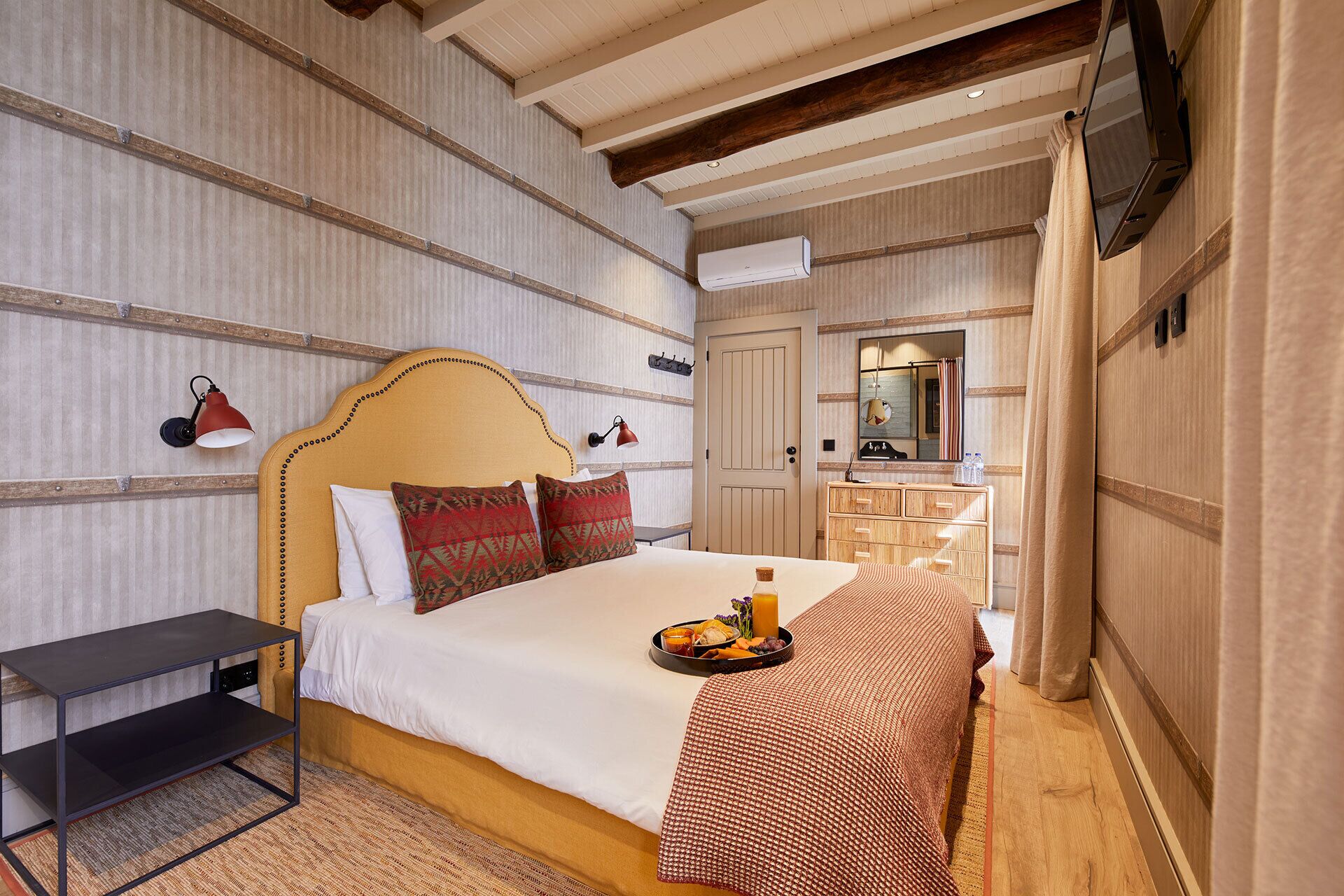 Ein Hotelzimmer mit Bett, Nachttisch und Frühstückswagen auf dem Bett.