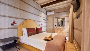 Ein Hotelzimmer mit Bett, Nachttisch und Frühstückswagen auf dem Bett.
