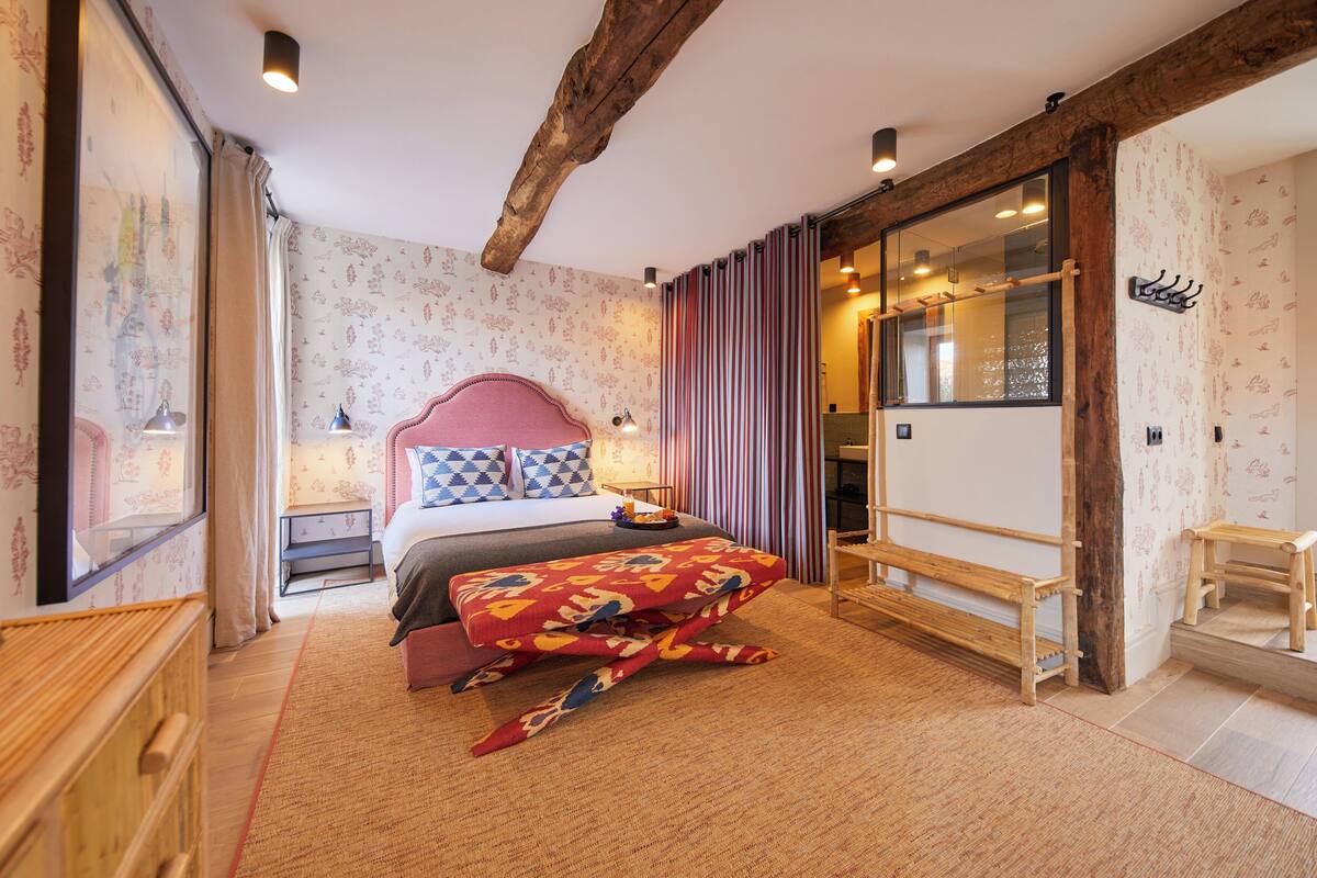 Ein Schlafzimmer mit einem Bett, Nachttischen, einem großen Spiegel und einer hölzernen Bank.