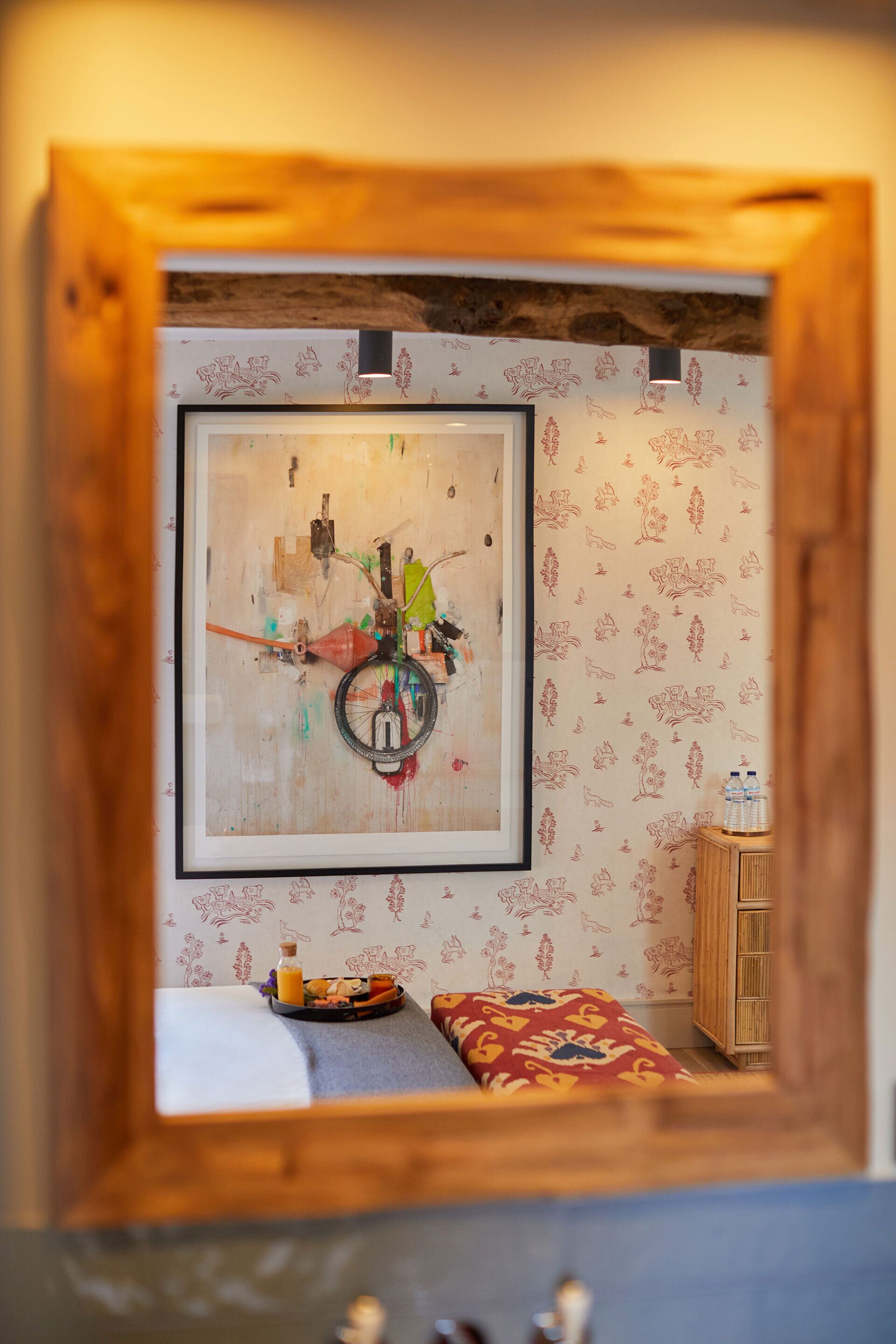 A room with a large abstract painting on the wall, a wooden cabinet, and a patterned wall.