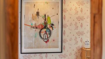 A room with a large abstract painting on the wall, a wooden cabinet, and a patterned wall.