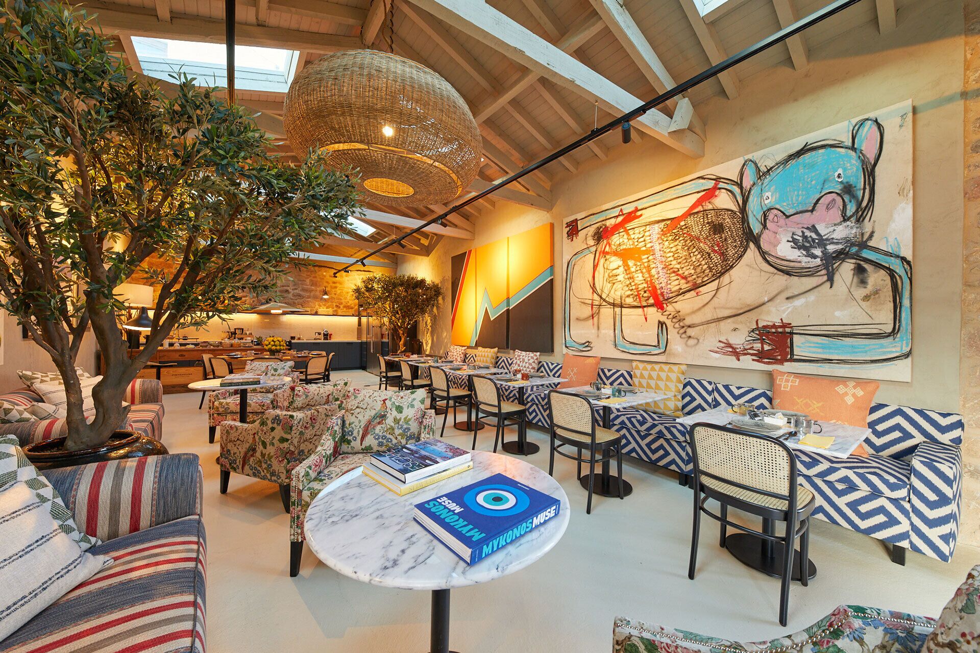 A cozy indoor dining area with round tables, cushioned seating, and a large wall mural.
