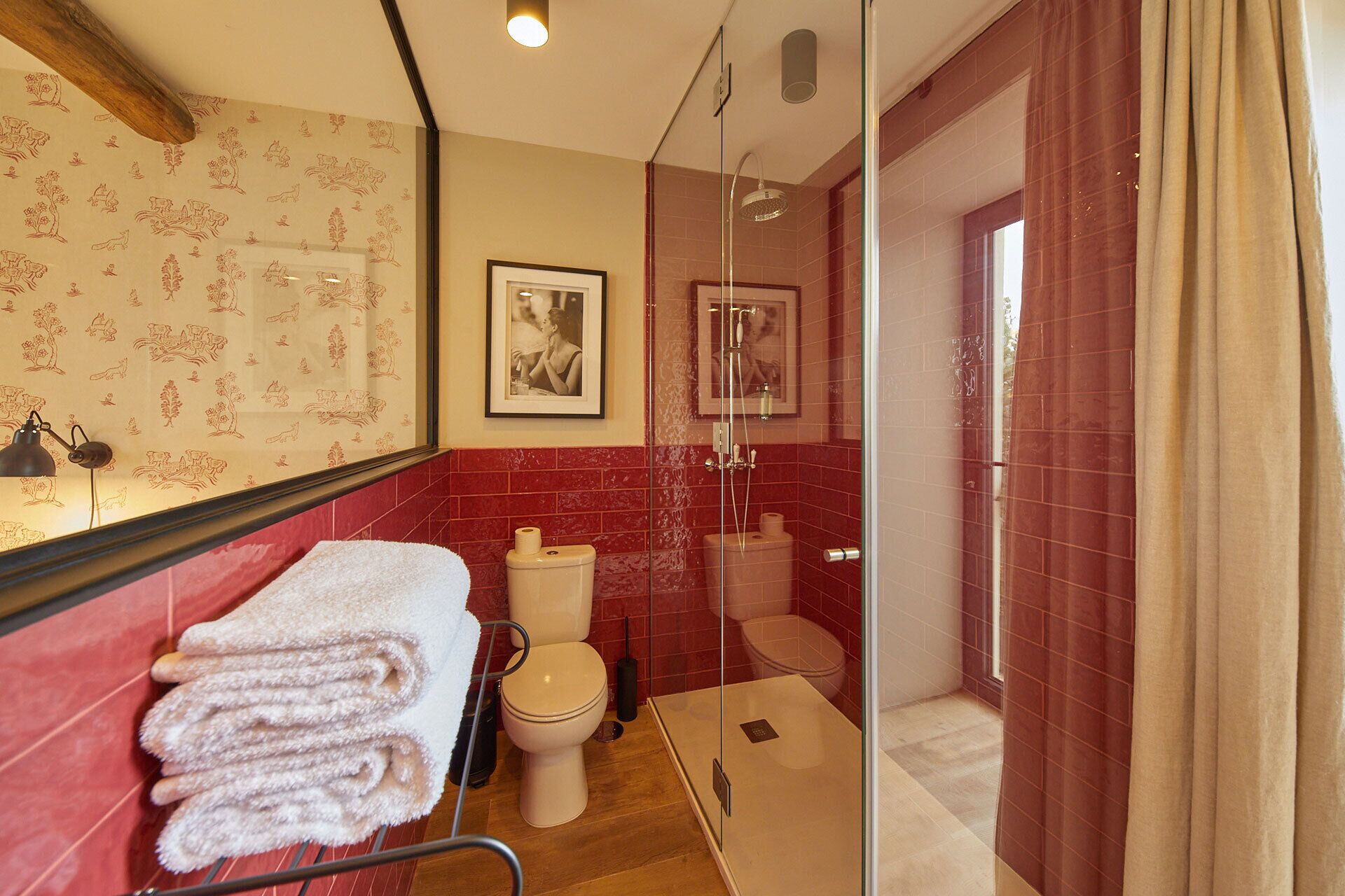 A bathroom with a glass shower enclosure, a toilet, and a sink.