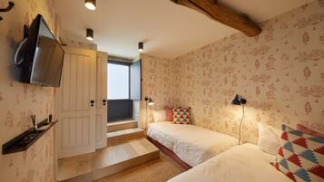 A bedroom with two beds, a TV, and a staircase leading to a balcony.