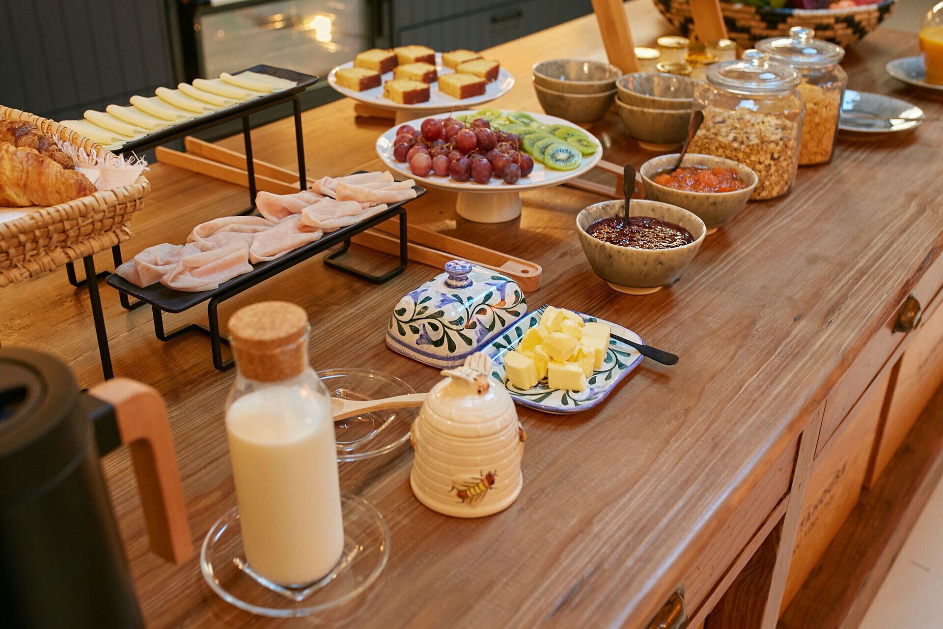 A buffet table with various food items including bread, cheese, fruits, and condiments.