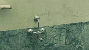 A bathroom with a marble wall, a sink with a faucet, and a bucket labeled "NAKODA". - Viji Towers Tiruvannamalai (Tiruvannamalai)