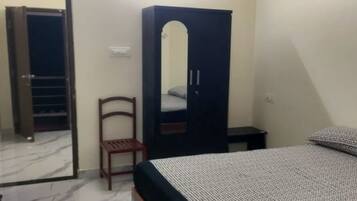 Cozy retreat with a bed, wardrobe, and chair, perfect for a restful stay.