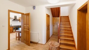 A spacious hallway with wooden flooring, a wooden staircase, and a view into a kitchen area. - Charming Villa With Internet (Varvažov)