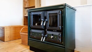 A large, dark green, vintage-style stove with four doors and a front panel, placed on a wooden floor with a wicker basket nearby. - Charming Villa With Internet (Varvažov)