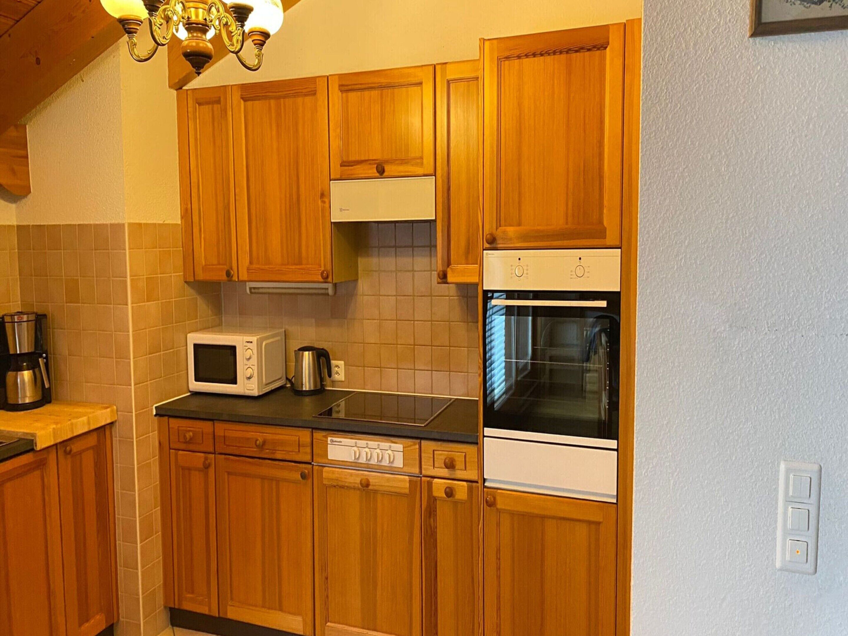 A kitchen with wooden cabinets, a microwave, a coffee maker, and an oven.