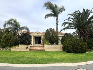 A house with a front entrance, a paved driveway, and a well-maintained lawn.