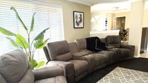 A sectional sofa with a geometric-patterned rug, a large plant, and a framed artwork on the wall. - 22 Home Sweet Home Coastal Currambine (Currambine)