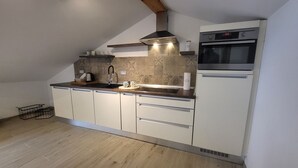 Eine kompakte Küche mit eingebautem Ofen, Dunstabzugshaube aus Edelstahl und einer Holz Arbeitsplatte.