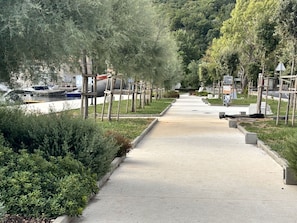 A pathway leading to a marina with boats docked, surrounded by greenery and trees. - Apartment Bakar 2 Seaside Croatia (Bakar)