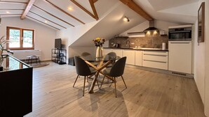 Eine moderne Küche mit Essbereich, Holzbalken und einem großen Fenster.