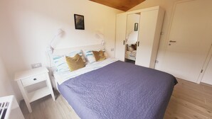 Ein Schlafzimmer mit Bett, Nachttisch, Kleiderschrank und Spiegel.