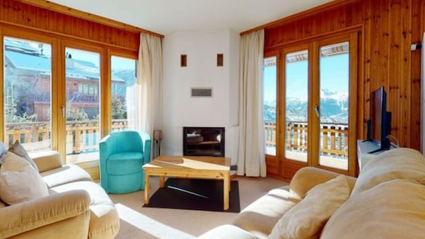 A spacious living room with a fireplace, large windows, and a balcony with a view of mountains. - Beaulieu F 014 Center Apartment 5 Pers (Veysonnaz)