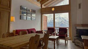 A cozy room with a wooden ceiling, a dining table with chairs, a red sofa, and a fireplace. - Beaulieu F 014 Center Apartment 5 Pers (Veysonnaz)